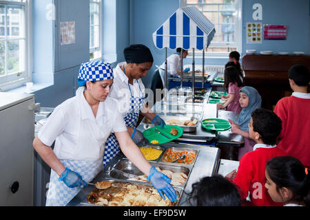 Mittagessen in der UK State Primary School Dinner Damen servieren Grundschulkinder gesundes Essen in der Primary School, London Stockfoto