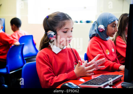 Mädchen in der Grundschule eine Online-Mathe-Klausur zu tun und mit ihren Fingern zählen Stockfoto