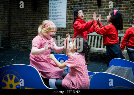 Kinder spielen Clap Hands Schule Hof spielen Kinder im Grundschulalter in der Grundschule Stockfoto