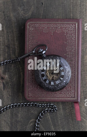 Taschenuhr auf altes Buch über rustikale Holz Hintergrund Stockfoto