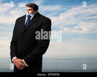 Fantasy Bild des Menschen im Business-Anzug in der Nähe von Meer, dessen Kopf nach unten in seinen Körper geschrumpft ist Stockfoto