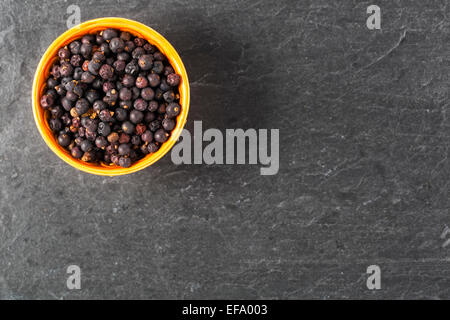 Schüssel mit Wacholderbeeren auf Steinoberfläche mit Textfreiraum. Stockfoto