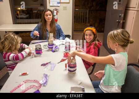 Unterstützt von einem Freiwilligen, Kinder in der katholischen Kirche St. Timothy, machen Laguna Niguel, CA, dekorierte Gläser von nummerierten Zungenspatel als Methode zur Verfolgung von Tagen auf dem Adventskalender. Advent symbolisiert die Zeit der Vorbereitung auf die Feier der Geburt Jesu zu Weihnachten. Beachten Sie, dass am Tisch Künstlerbedarf Stockfoto