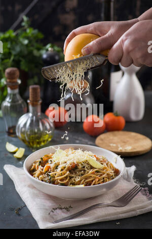 geriebener Käse über Spaghetti mit Tomatensauce und Kräutern Stockfoto