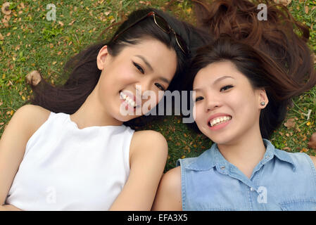 Portrait von zwei schöne, junge Frauen, legen Sie sich auf Rasen Stockfoto