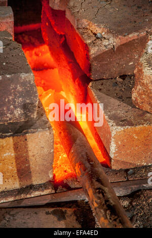 Eine Eisenstange ist beheizten Red-Hot in der Schmiede von einer Schmiede. Hinweis Schamottesteine. Stockfoto