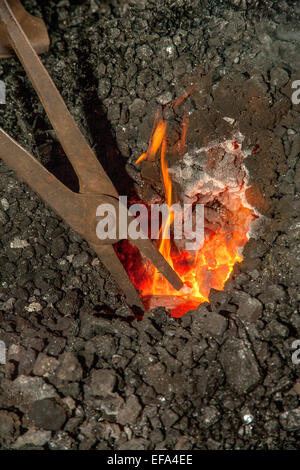 Zange halten Eisen wird beheizten Red-Hot in der Kohle-Schmiede von einer Schmiede. Stockfoto