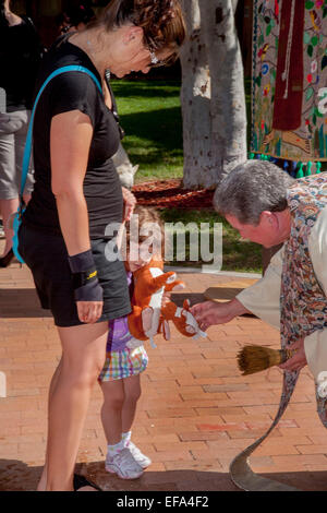 Als ihre Mutter ihre Hand hält segnet ein Priester ein kleines Mädchen Spielzeug Hase bei der Segnung der Tiere auf die fest des St. Franziskus von Assisi St. Timothy katholische Kirche, Laguna Niguel, CA. beachten Sie Weihwasser sprinkler Stockfoto