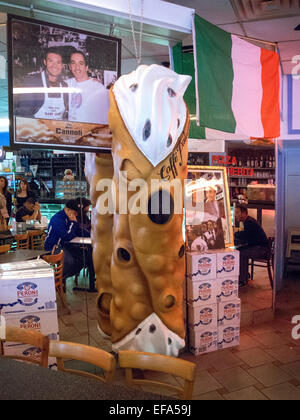 Ein riesiges Modell eines Canoli schmückt ein Restaurant im New Yorker Stadtteil Little Italy in Manhattan. Cannoli sind italienische Gebäck Desserts bestehend aus röhrenförmigen Muscheln von frittierten Teig, gefüllt mit einer süßen, cremigen Füllung in der Regel mit Ricotta-Käse. Beachten Sie die italienische Flagge. Stockfoto