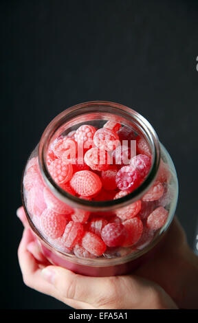 Rote Süßigkeiten in einem Bonbon-Glas mit schwarzem Hintergrund Stockfoto