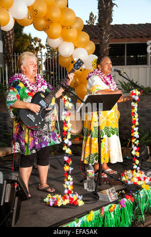 Dekoriert mit Luftballons und Kunstblumen, führen zwei hawaiische Musiker bei einem Hula-Festival in den Ruhestandsgemeinschaft von Laguna Woods, CA. beachten Sie native Hawaiian Frau auf der rechten Seite. Stockfoto