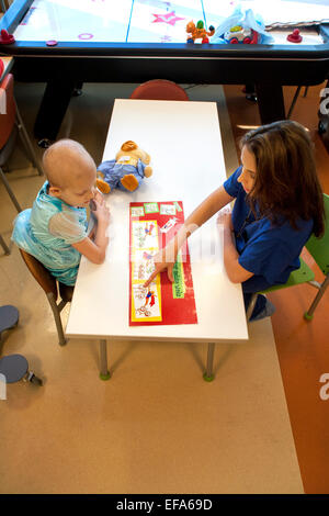 Ein Kind Leben Specialist bei CHOC Kinderklinik, in Orange, Kalifornien, nutzt einen Superhelden-Comic, einen junges Mädchen Krebs zeigen Patienten wie Chemotherapie. Kind Leben Spezialisten unterstützen Patienten und Familien im Krankenhausumfeld. Hinweis: Glatze und Chemo-Ente, die die Platzierung eines intravenösen Schlauch "Hafen" für Chemotherapie-Medikamente zeigt. Stockfoto