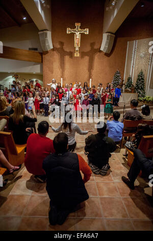 Gemischtrassig junge Kinder singen Weihnachtslieder während der Christmette am St. Timothy katholische Kirche, Laguna Niguel, CA. Hinweis Chorleiter. Stockfoto