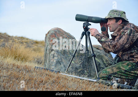 Junger Mann gekleidet in Tarnung scoping für Himalaya-Tahr in den südlichen Alpen, Neuseeland Stockfoto