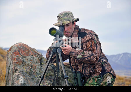 Junger Mann gekleidet in Tarnung scoping für Himalaya-Tahr in den südlichen Alpen, Neuseeland Stockfoto