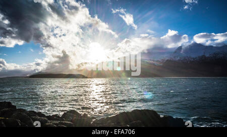 Sunbust durch dramatische Wolken am Meer im Südosten Alaskas mit Schnee bedeckt die Berge im Hintergrund. Stockfoto