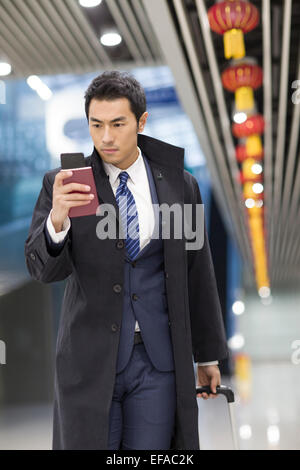 Junge Unternehmer Wandern im Flughafen mit Pass und Smartphone Stockfoto