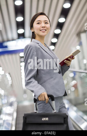 Junge Geschäftsfrau mit Koffer auf Rolltreppe Stockfoto