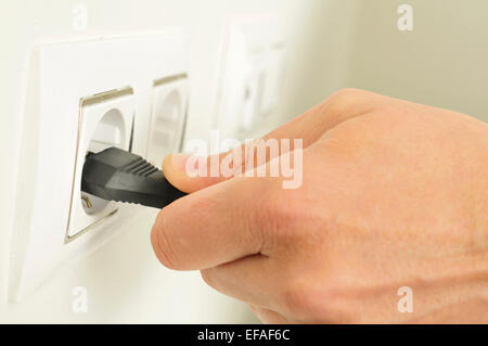 Nahaufnahme der Hand eines Mannes einstecken oder Abziehen eines elektrischen Steckers in die Steckdose Stockfoto