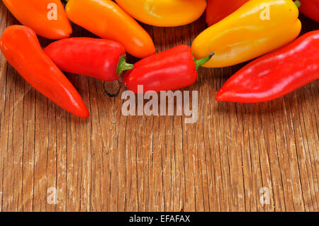 einige Paprika verschiedene Farben, Orange, rot und gelb auf einem rustikalen Holztisch Stockfoto