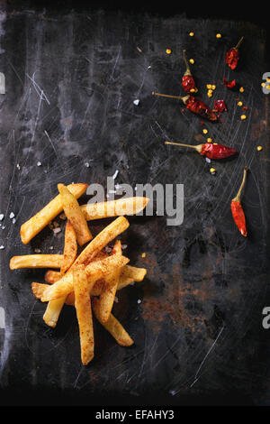 Bratkartoffeln mit Meersalz und Red hot Chili Pfeffer über schwarze Metall Oberfläche Stockfoto