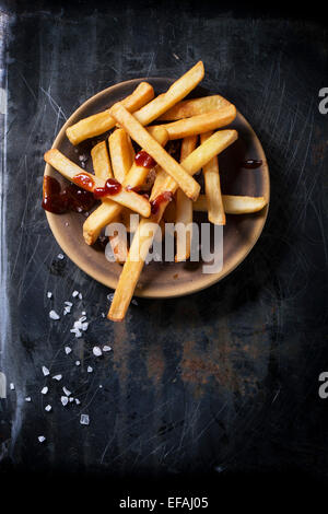 Keramik Teller mit Pommes Frites mit Meersalz und Ketchup auf schwarzem Hintergrund, Ansicht von oben Stockfoto