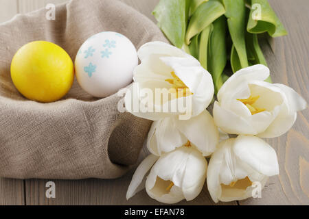 handbemalte Ostereier und weißen Tulpen auf Holztisch Stockfoto