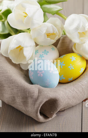 handbemalte Ostereier und weißen Tulpen auf Holztisch Stockfoto