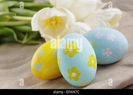 handbemalte Ostereier und weißen Tulpen auf Holztisch Stockfoto