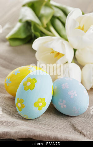 handbemalte Ostereier und weißen Tulpen auf Holztisch Stockfoto