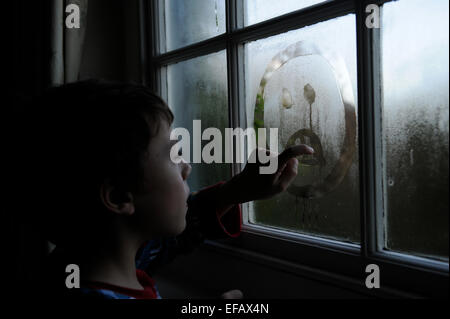 10 Jahre Alter junge Gesichter in der Kondensation auf ein Fenster zeichnen Stockfoto