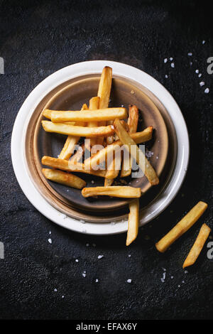 Keramik Teller mit Pommes Frites mit Meersalz auf schwarzem Hintergrund, Ansicht von oben Stockfoto