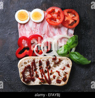 Zutaten für Sandwich mit Schinken, Eiern, Gemüse und Ketchup auf schwarzem Hintergrund. Ansicht von oben Stockfoto