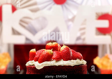 Roter Samt-Kuchen mit Erdbeeren und Inschrift Liebe im Hintergrund Stockfoto