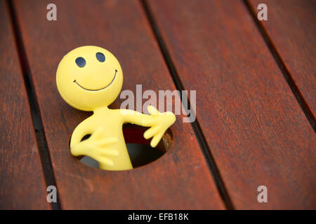 Gelbes Smiley-Mann im Urlaub in den äußeren Hebriden - hat er hier durch das Dach-Loch in einen Terrassentisch gefallen Stockfoto