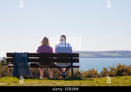 Paar, sitzen auf der Prachtnelke bei Alum Chine, Bournemouth, Blick auf das Meer und die Aussicht zu bewundern, im März. Stockfoto