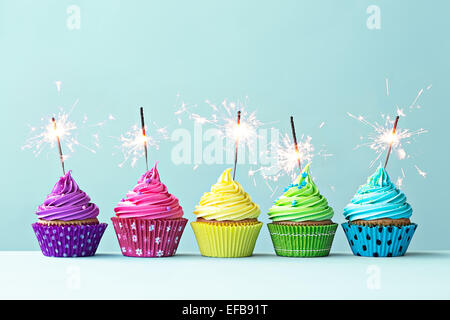 Reihe von bunten Cupcakes mit Wunderkerzen Stockfoto