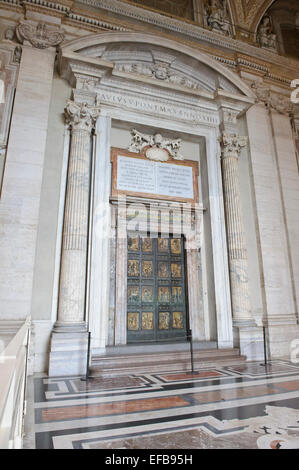 Eine dicke Stahltür mit religiösen Schnitzereien an St. Peter Basilika, Vatikanstadt, Rom, Italien. Stockfoto