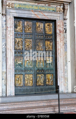 Eine dicke Stahltür mit religiösen Schnitzereien an St. Peter Basilika, Vatikanstadt, Rom, Italien. Stockfoto