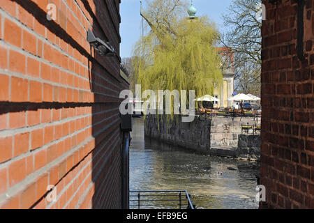 Blick durch eine Lücke zwischen den Wänden von den Gebäuden der historischen Mühle am Fluss Ilmenau und ein Open-Air-Pub, 21. April 2013 Stockfoto