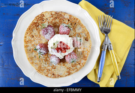 Laskiaispulla Pancake Pfannkuchen Dienstag mit Erdbeeren und Sahne auf dunklen blau Vintage shabby chic Tisch. Stockfoto