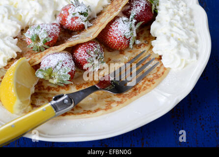 Laskiaispulla Pancake Pfannkuchen mit Erdbeeren und Sahne auf dunkel blaue Vintage shabby chic Tabelle, Closeup Dienstag. Stockfoto