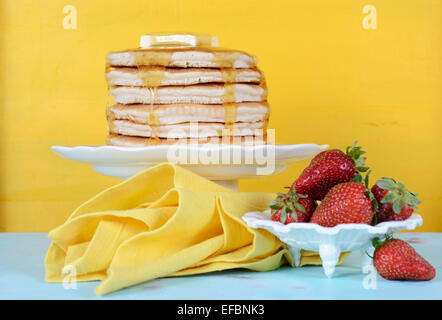 Laskiaispulla Pfannkuchen Dienstag Stapel von Pfannkuchen mit Butter, Honig und Erdbeeren auf gelb und Aqua blue Vintage Tisch Stockfoto