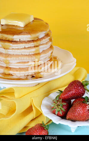 Laskiaispulla Pfannkuchen Dienstag Stapel von Pfannkuchen mit Honig und Butter auf gelb und Aqua blau Vintage shabby chic Tisch, vertikale Stockfoto