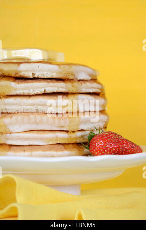 Laskiaispulla Pfannkuchen Dienstag Stapel von Pfannkuchen mit Honig und Butter auf gelb und Aqua blau Vintage shabby chic Tisch, vertikale schließen Stockfoto