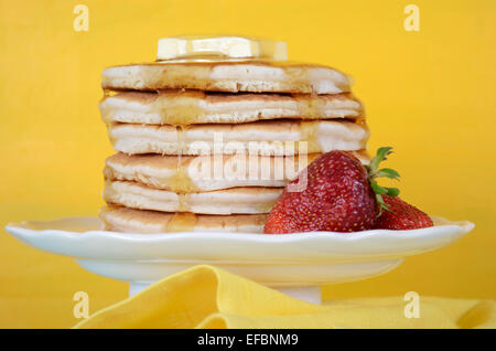 Laskiaispulla Pfannkuchen Dienstag Stapel von Pfannkuchen mit Honig und Butter auf gelb und Aqua blau Vintage shabby chic Tisch, Closeup. Stockfoto