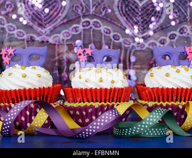 Karneval-Cupcakes mit lila Maske Topper auf rustikalen Stil dunkel blau Vintage Holz Tisch. Stockfoto