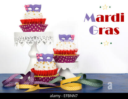 Karneval-Cupcakes mit lila Maske Topper auf rustikalen Stil dunkel blau Vintage Holz Tisch. Stockfoto