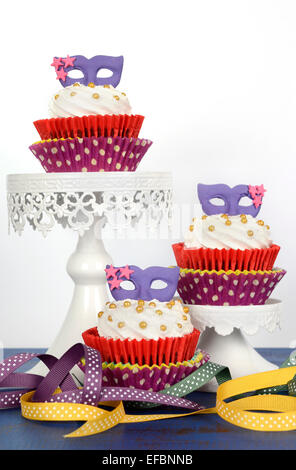 Karneval-Cupcakes mit lila Maske Topper auf rustikalen Stil dunkel blau Vintage Holz Tisch. Stockfoto