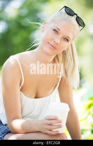 Attraktive junge Mädchen trinken Kaffee im park Stockfoto